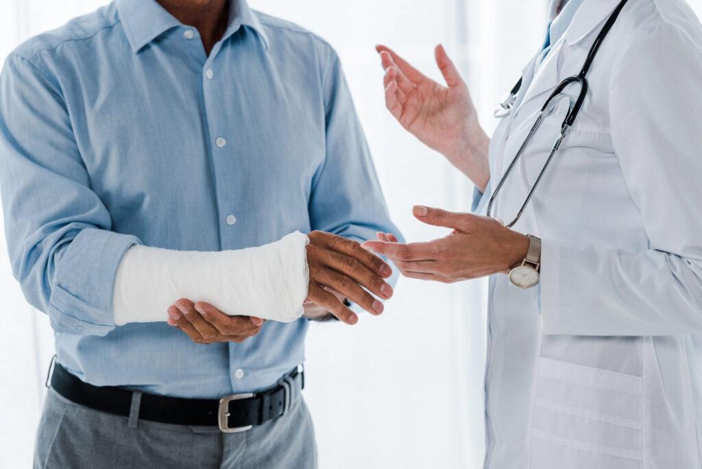 Doctor helping patient with injured arm in medical consultation.