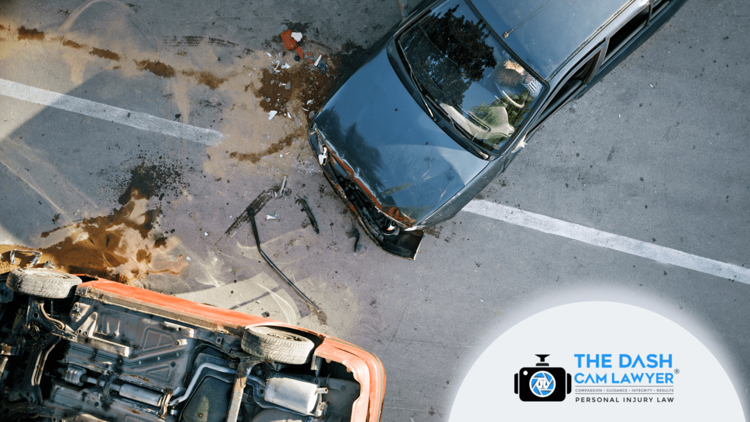 Overhead view of a serious two-car accident on a roadway showing a damaged black sedan, an overturned vehicle, debris scattered across the pavement, and visible crash impact marks