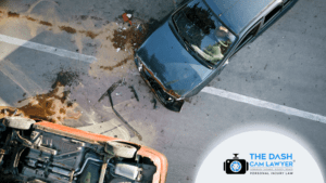 Overhead view of a serious two-car accident on a roadway showing a damaged black sedan, an overturned vehicle, debris scattered across the pavement, and visible crash impact marks